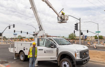 Industrial vehicle with a crane and basket working on a streetlight.