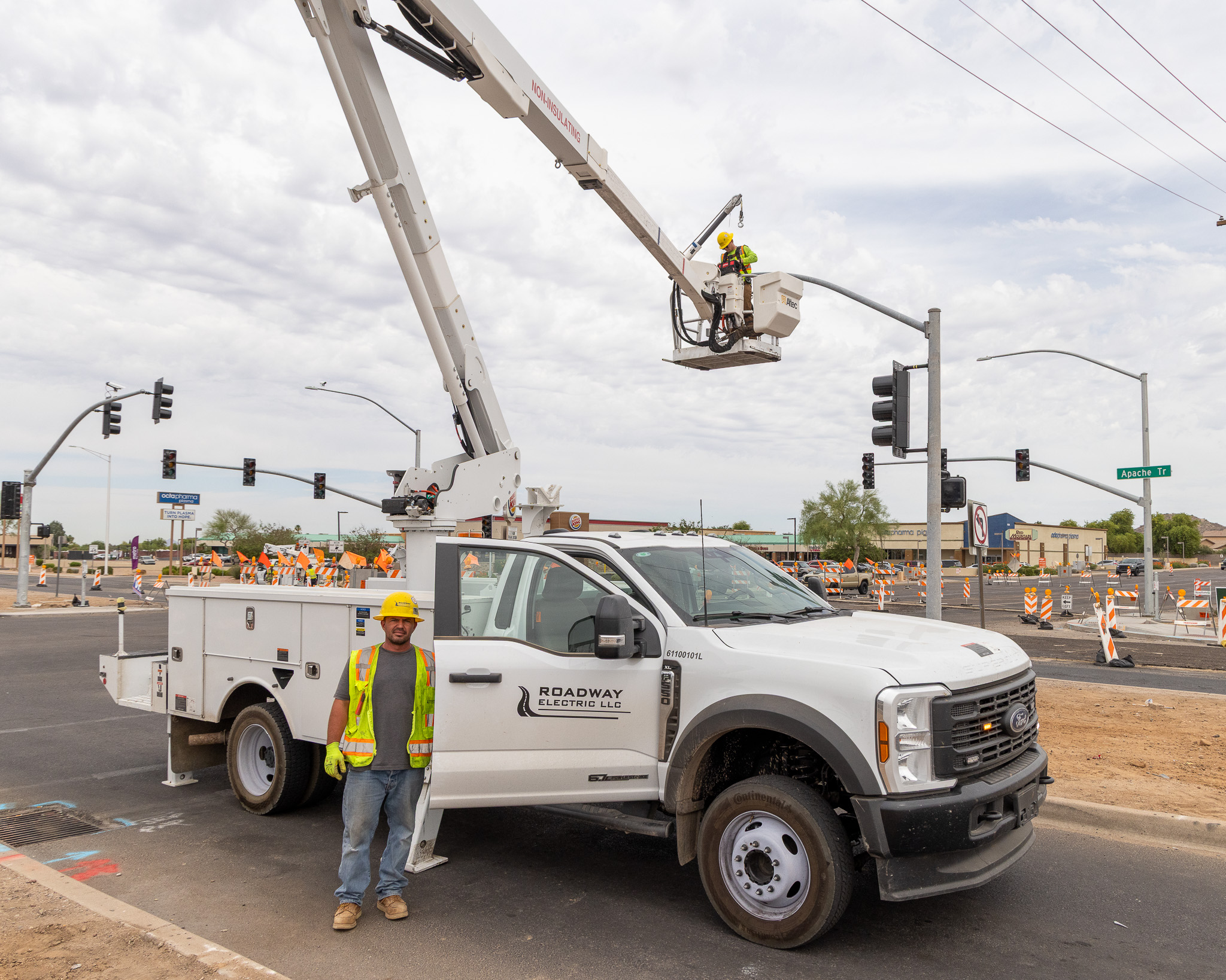 Industrial vehicle with a crane and basket working on a streetlight.